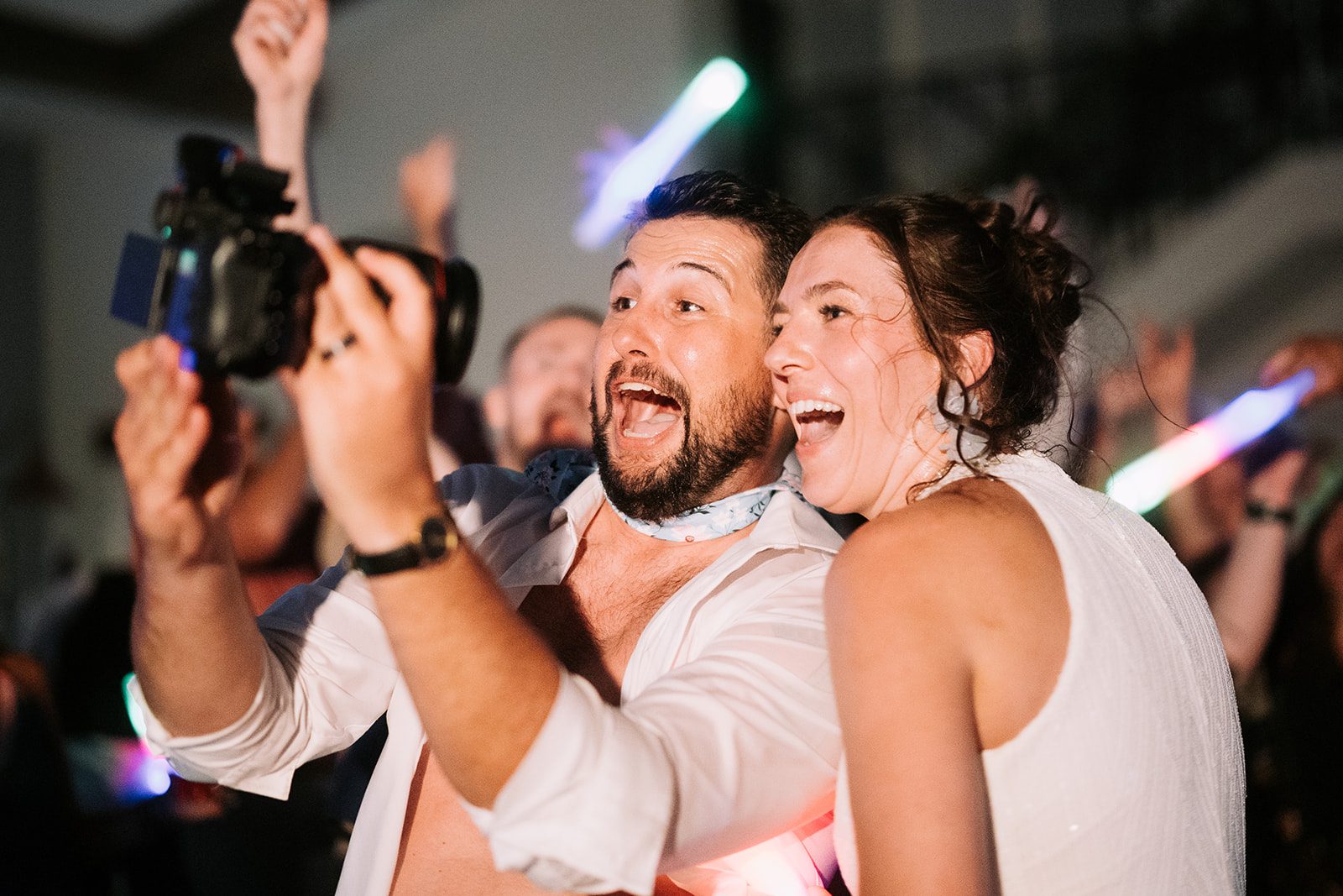 bride and groom recording themselves with photographers camera on the ance floor of their reception with dim light at riverbridge event center spanish fork utah