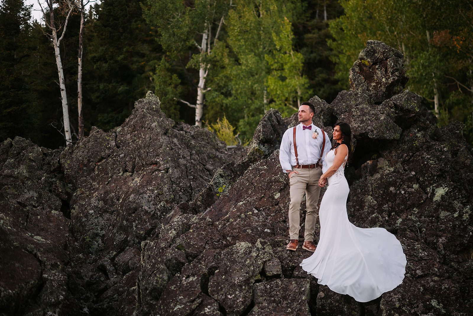 newly married husband and wife posing for a surreal photo in panguitch utah for elopement wedding in black volcanic rock setting